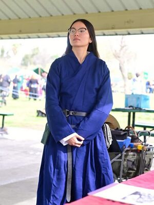 Cau Jyun is pictured at Academia Draconis 2024, Anno Societatus 58, wearing a blue Ming dynasty Chinese men's robe.